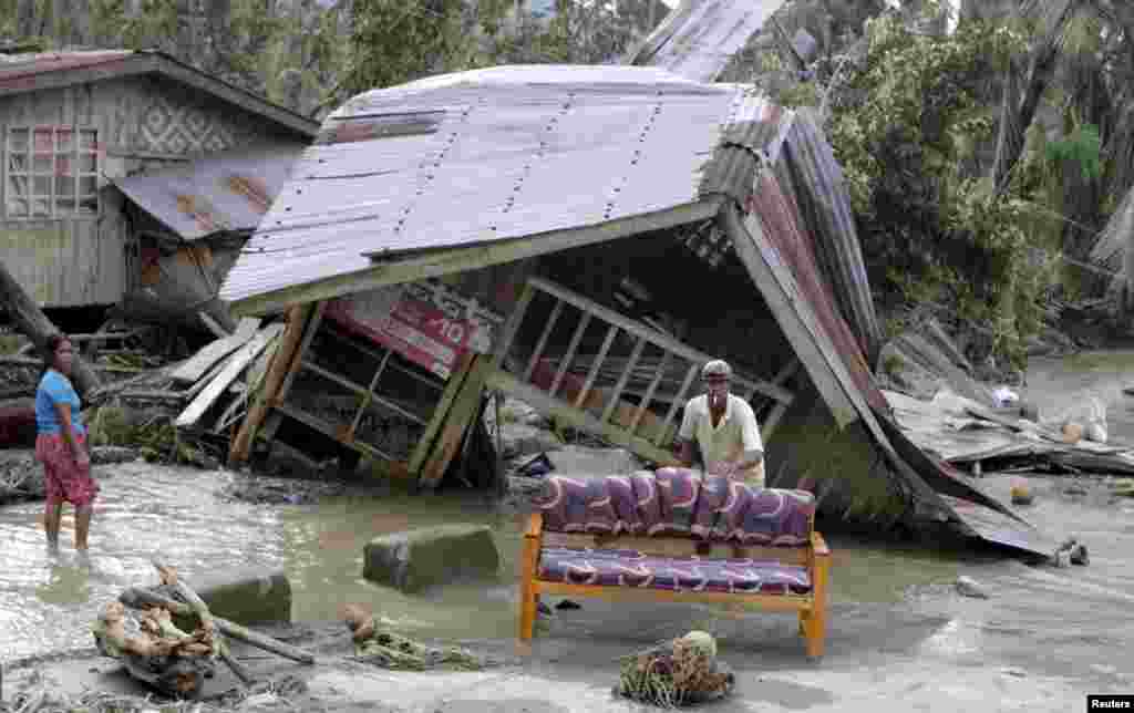 Residents clean their sofa outside their destroyed house after Typhoon Bopha hit Compostela Valley, Philippines, December 5, 2012. 