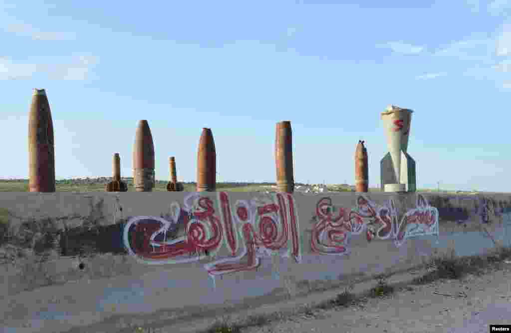 A view of graffiti reading, &quot;Buying all kinds of shells&quot; under remnants of shells placed at the edge of a street in Kafruma village, in Idlib province, Syria, April 7, 2015.