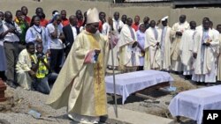 Clergymen gather around the coffins of the victims of the Christmas day bombing at St Theresa Catholic Church Madalla, during a mass funeral for the victims, outside Nigeria's capital Abuja, February 1, 2012