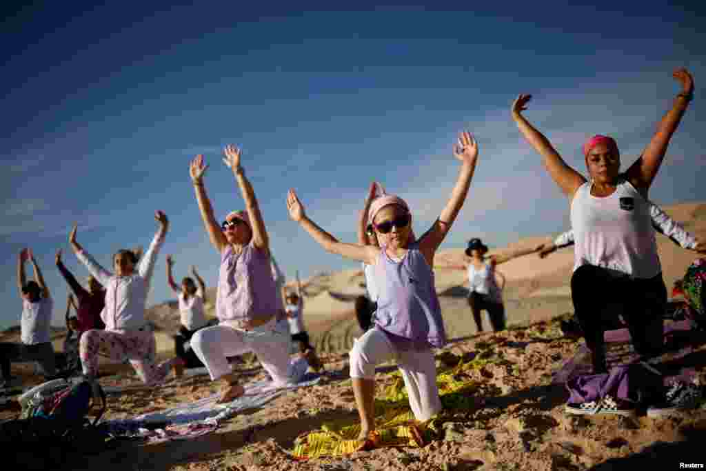 Yoga enthusiasts take part in a class in honor of victims of the COVID-19, at the Samalayuca dunes on the outskirts of Ciudad Juarez, Mexico, July 3, 2021.