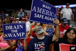 File - Supporters hold signs as President Donald Trump speaks during a rally Aug. 21, 2018, in Charleston, W.Va.