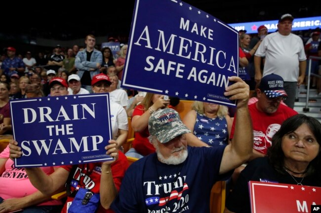 Supporters hold signs as President Donald Trump speaks during a rally Aug. 21, 2018, in Charleston, W.Va.