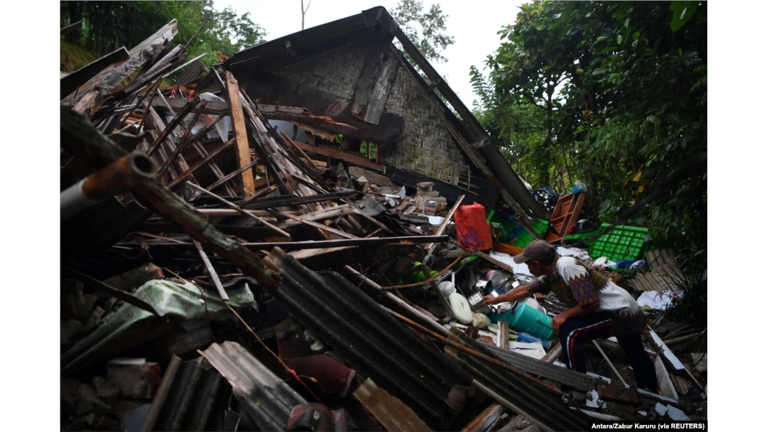 Seorang pria menyelamatkan barang miliknya di sebuah rumah yang rusak akibat gempa bumi di Lumajang, Jawa Timur, 11 April 2021, sebagai ilustrasi. (Foto: Antara/Zabur Karuru via REUTERS)
