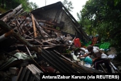 Seorang pria menyelamatkan barang miliknya di sebuah rumah yang rusak akibat gempa bumi di Lumajang, Jawa Timur, 11 April 2021. (Foto: Antara/Zabur Karuru via REUTERS)