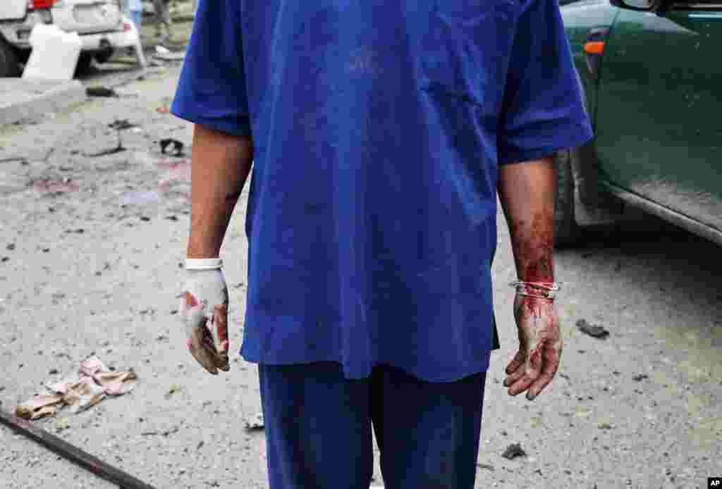 An Afghan health worker stands after a suicide attack that struck the convoy of presidential candidate Abdullah Abdullah in Kabul, June 6, 2014. 