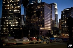 Homeless tents are dwarfed by skyscrapers as 63-year-old Vincent, who gave only his first name, sorts his belongings, Dec. 1, 2017, in Los Angeles. Vincent said he never had to worry about getting a job as a young man. "Things ain't the way they were any