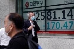 Men walk past an electronic stock board showing Japan's Nikkei 225 index at a securities firm in Tokyo Monday, July 27, 2020.