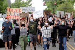 Protesters hold their hands up as they march near Wright Park, June 5, 2020, in Tacoma, Wash.