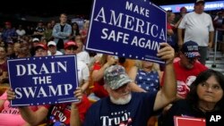 FILE - Supporters hold signs as President Donald Trump speaks during a rally Aug. 21, 2018, in Charleston, West Virginia.