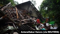 Seorang pria menyelamatkan barang miliknya di sebuah rumah yang rusak akibat gempa bumi di Lumajang, Jawa Timur, 11 April 2021. (Foto: Antara/Zabur Karuru via REUTERS)