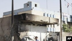 An Iraqi policeman walks past a crater caused by a car bomb attack in front of a police station in Baghdad, Iraq, October 12, 2011.