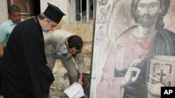 In this photo taken on Sunday, April 20, 2014 and released by the Syrian official news agency SANA, Syrian President Bashar Assad, center, removes a book from the ground next to a religious icon during his visit to the Christian village of Maaloula, near Damascus, Syria. (AP Photo/SANA)