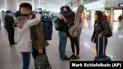 资料照片：2020年3月28日星期六，被驱逐的《华尔街日报》记者在离开北京前拥抱同事。