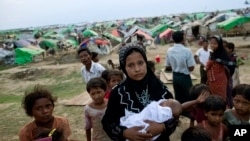 在若开邦实兑，一名在缅甸境内流离失所的罗兴亚妇女抱着婴儿站在一群孩子的中间，他们身后是临时帐篷营地。（资料照）