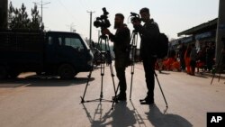 FILE - Afghan journalists film at the site of a bombing attack in Kabul, Afghanistan, Feb. 9, 2021. 
