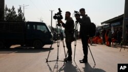 FILE - Afghan journalists film at the site of a bombing attack in Kabul, Afghanistan, Feb. 9, 2021. 