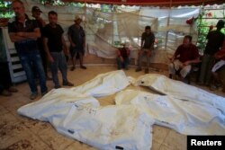 People mourn next to bodies at Nasser Hospital following an Israeli strike in Khan Younis in the southern Gaza Strip, July 13, 2024.