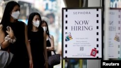 A sign advertising job openings is seen while people walk into the store in New York City, Aug. 6, 2021. 