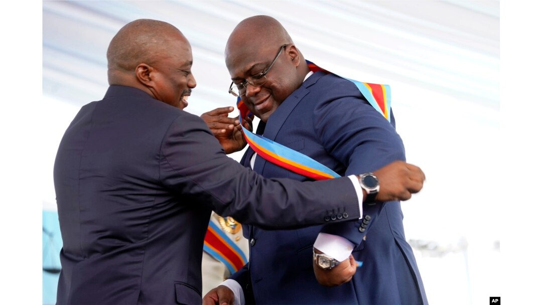 Congolese President Felix Tshisekedi, right, receives the presidential sash from outgoing president Joseph Kabila after being sworn in in Kinshasa, Democratic Republic of the Congo, Thursday Jan. 24, 2019.