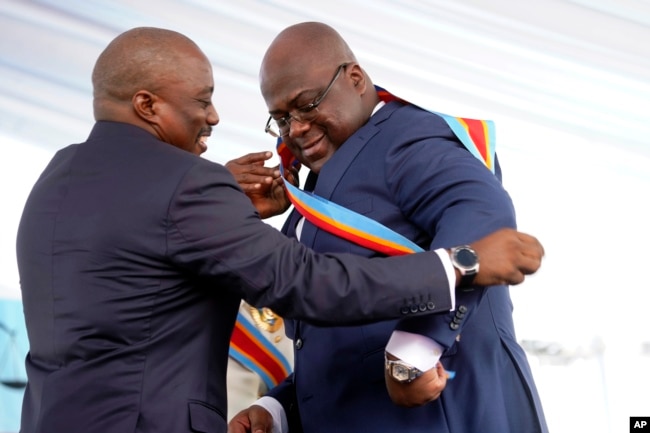 Congolese President Felix Tshisekedi, right, receives the presidential sash from outgoing president Joseph Kabila after being sworn in in Kinshasa, Democratic Republic of the Congo, Thursday Jan. 24, 2019.