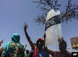 A protester holds up a police shield at a rally in front of the military headquarters in the capital Khartoum, Sudan, Monday, April 8, 2019.