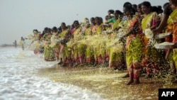 FILE - Indian women throw flowers into the sea as an offering during a ceremony for the victims of the 2004 tsunami at Marina Beach in Chennai, Dec. 26, 2016.