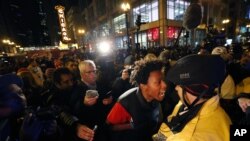 Lamon Reccord, second from right, yells at a Chicago police officer "Shoot me 16 times" as he and others march through Chicago's Loop Wednesday, Nov. 25, 2015.