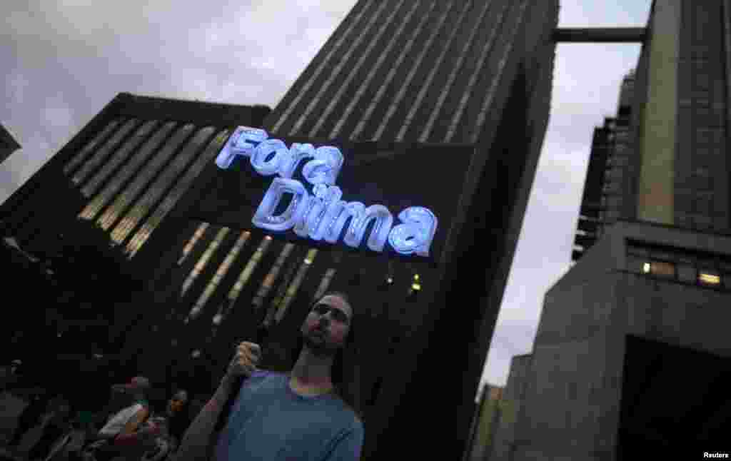 Manifestante carrega placa iluminada durante protestos.