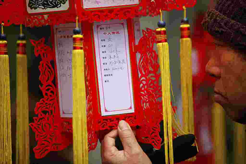 A parent looks at a red lantern with personal information displayed during a Valentine's Day event at the People's Park in Shanghai, February 14, 2012. The event is organized by the local government to help parents look for dating opportunities for their