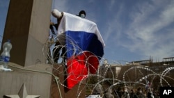 4月7日，一面戴上面罩手持俄羅斯國旗的示威者爬上烏克蘭涅茨克州政府大樓。