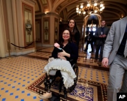 Sen. Tammy Duckworth, D-Ill., with her baby Maile Pearl Bowlsbey leaves the Senate floor after a voting on Capitol Hill in Washington, Thursday, April 19, 2018. (AP Photo/Manuel Balce Ceneta)