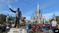 FILE - In this Jan. 9, 2019 photo, guests watch a show near a statue of Walt Disney and Micky Mouse in front of the Cinderella Castle at the Magic Kingdom at Walt Disney World in Lake Buena Vista, part of the Orlando area in Fla. 