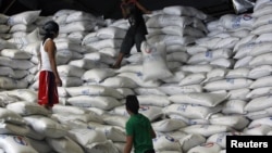 A worker passes a sack of rice to other workers inside a National Food Authority (NFA) warehouse in Taguig City, south of Manila, the Philippines, March 26, 2012. 