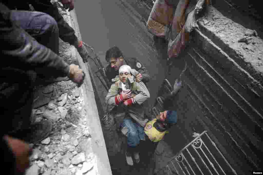 Syria Civil Defense members help an unconscious woman from a shelter in the besieged town of Douma, Eastern Ghouta, Damascus, Syria.