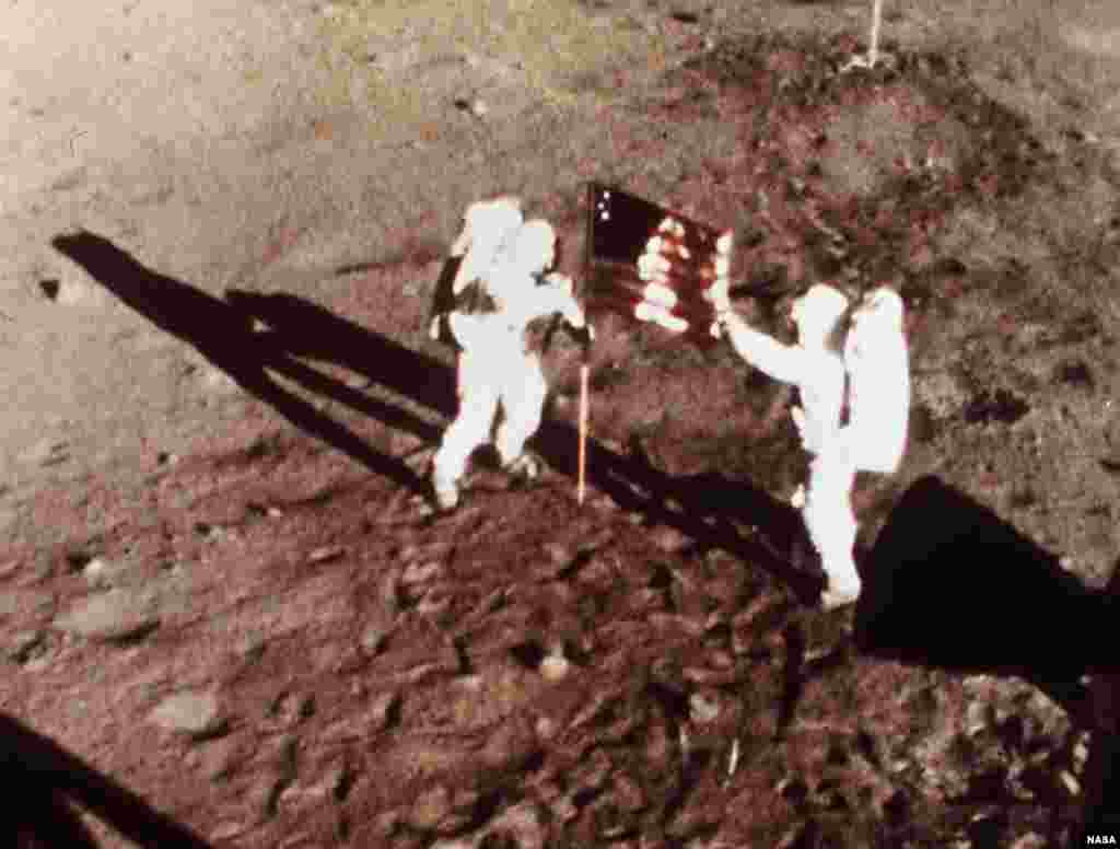 Dalam foto tertanggal 20 Juli 1969, para astronot Apollo 11 Neil Armstrong dan Edwin E. &quot;Buzz&quot; Aldrin, manusia-manusia pertama yang mendarat di bulan, menancapkan bendera AS di permukaan bulan. Foto diambil dengan kamera film 16 mm.