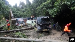 Tim penyelamat membersihkan puing-puing di dekat kendaraan yang terdampak longsor yang menewaskan sejumlah orang di Sibolangit, Sumatera Utara, Kamis, 28 November 2024. (Foto AP/Binsar Bakkara)