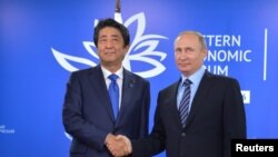 아베 신조(왼쪽) 일본 총리와 블라디미르 푸틴 러시아 대통령이 지난 9월 초 블라디보스토크 '동방경제포럼' 현장에서 만나 악수하고 있다. (자료사진)
