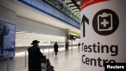 Un viajero pasa frente a un cartel indicando dónde hay un puesto de testeo en el aeropuerto de Heathrow, en Londres, el 18 de enero de 2021.