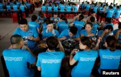 Para pekerja perempuan makan siang bersama rekan-rekan pria di pabrik garmen Maxport di Provinsi Thai Binh, Vietnam, 13 Juni 2019. (Foto: Reuters)