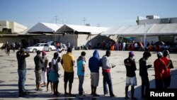 Migrants from Haiti, who returned to the Mexican side of the border to avoid deportation, queue for breakfast at a shelter set by the National Migration Institute (INM) in Ciudad Acuna, Sept. 25, 2021. 