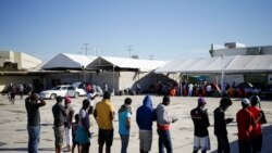 Migrants from Haiti, who returned to the Mexican side of the border to avoid deportation, queue for breakfast at a shelter set by the National Migration Institute in Ciudad Acuna, Sept. 25, 2021.