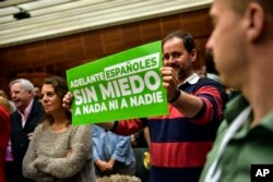 FILE - A supporter of Santiago Abascal, leader of Spanish far-right party Vox, shows a banner reading ''Spaniards, Forward. Without fear of anything or anyone,'' during a campaign meeting in San Sebastian, northern Spain, April 13, 2019.