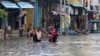 Sebuah keluarga mengarungi jalan yang tergenang banjir di Chennai, India, Rabu, 25 November 2020. Pada 19 November 2021, pihak berwenang negara bagian Andhra Pradesh, India mengatakan sedikitnya 17 orang tewas dan puluhan dilaporkan hilang setelah hujan lebat. (Foto: AP)