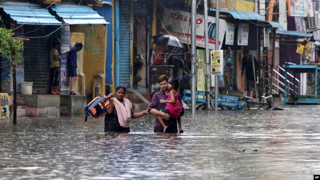Sebuah keluarga mengarungi jalan yang tergenang banjir di Chennai, India, Rabu, 25 November 2020. Pada 19 November 2021, pihak berwenang negara bagian Andhra Pradesh, India mengatakan sedikitnya 17 orang tewas dan puluhan dilaporkan hilang setelah hujan lebat. (Foto: AP)