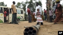 People walk past munitions laying in the street at Pugu-Majohe on the outskirt of Dar es Salaam, following several explosion that occurred at a military base, February 17, 2011