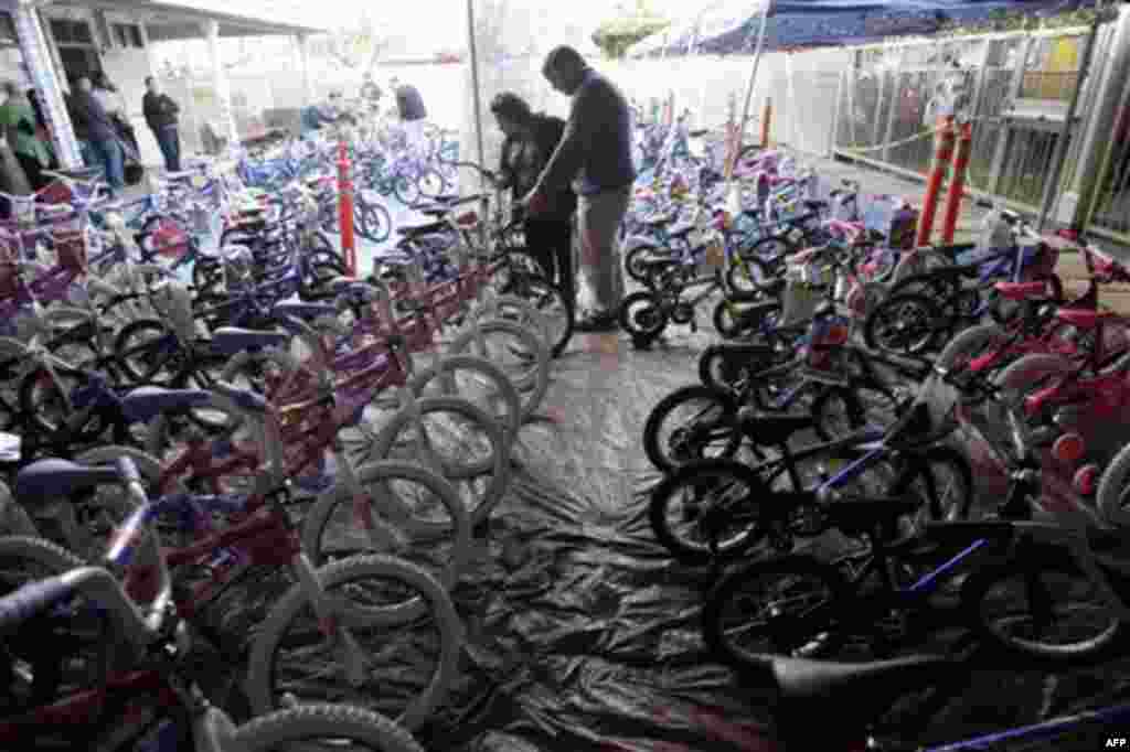 Mary Lazo, center left, an unemployed mother of two, looks for a bike as a Christmas present for her 7-year old daughter Daniela with the help of volunteer David Allen at Sacred Heart Community Service in San Jose, Calif., Wednesday, Dec. 22, 2010. The ce