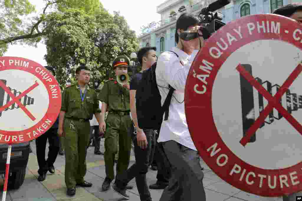 A police officer uses a speaker to order pedestrians, including journalists, to leave a closed area near the Chinese embassy in Hanoi, Vietnam, May 18, 2014.&nbsp; &nbsp;