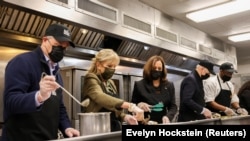 Presiden AS Joe Biden (kedua dari kanan) beserta Wakil Presiden Kamala Harris (ketiga dari kiri) didampingi oleh pasangannya masing-masing tampak sibuk membantu di dapur DC Central Kitchen di Washington D. C., pada 23 November 2021. (Foto: Reuters)