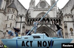 FILE - Extinction Rebellion climate activists raise a mast on their boat during a protest outside the Royal Courts of Justice in London, Britain, July 15, 2019.