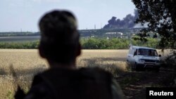 A Ukrainian army soldier looks on as local residents leave the village of Metalist near the eastern Ukrainian city of Luhansk July 11, 2014.